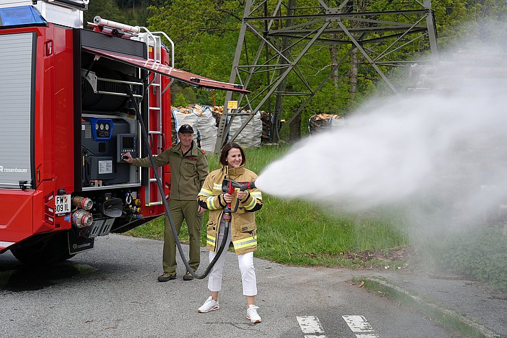 Mair neben Auto mit Schlauch; spritzt Wasser
