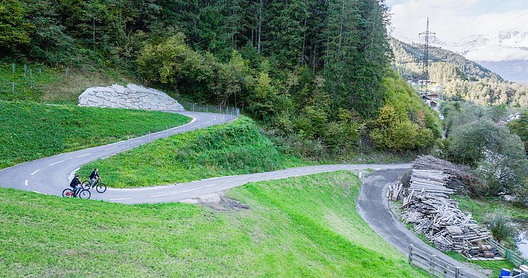 © Land Tirol/Raggl zwei RadfahrerInnen befahren einen Radweg in einer S-Kurve