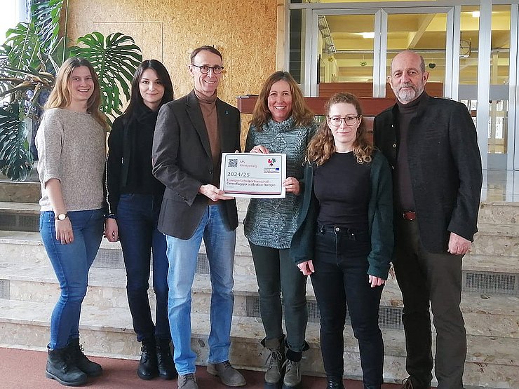 Personen halten Aufkleber, stehen in Schule bei Treppe
