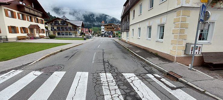 Foto einer beschädigten Straße mit Zebrastreifen und Gehsteig im Orstkern