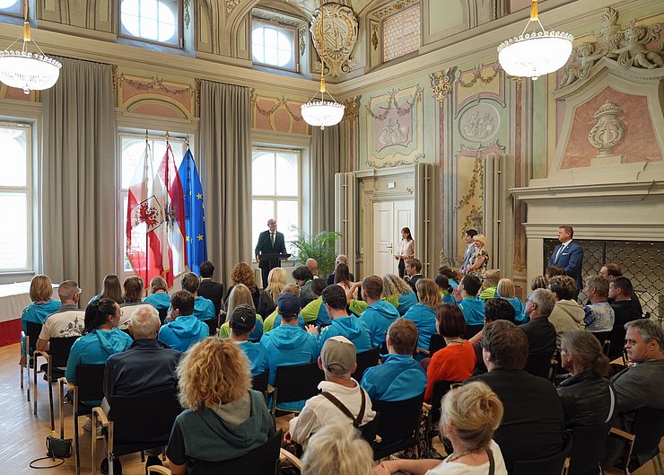 Parissaal im Landhaus mit Menschen sitzend; LH Mattle redend an Podium
