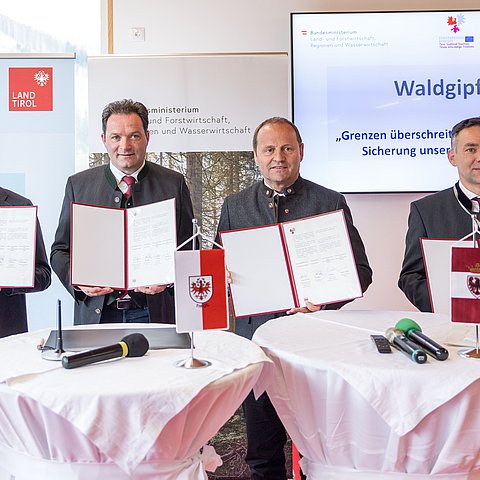 Personen stehen nebeneinander und halten Urkunde