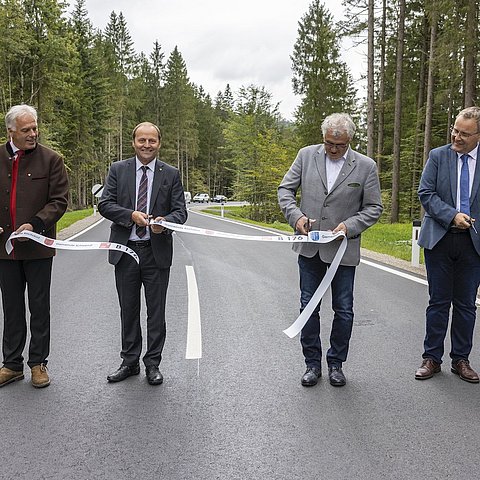 Von links Richard Dagn, Bürgermeister von Schwendt, Straßenbaureferent LHStv Josef Geisler, Gerhard Obermüller, Bürgermeister von Kirchdorf in Tirol, Jürgen Wegscheider vom Baubezirksamt Kufstein: Diese vier Personen stehen auf der sanierten Straße und durchschneiden zur Eröffnung ein Band.