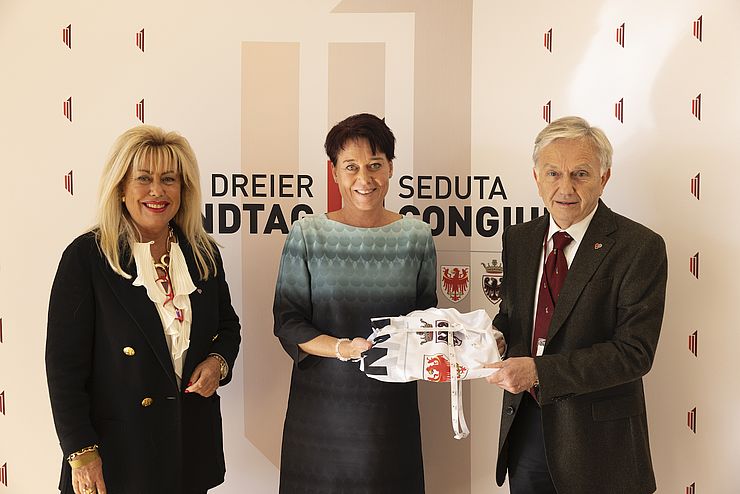 PräsidentInnen Sonja Ledl-Rossmann (Mitte) überreicht in Beisein ihrer Kollegin Rita Mattei (Südtirol) dem neuen geschäftsführenden Präsidenten Walter Kaswalder (Trentino) eine Dreier-Landtagsfahne.