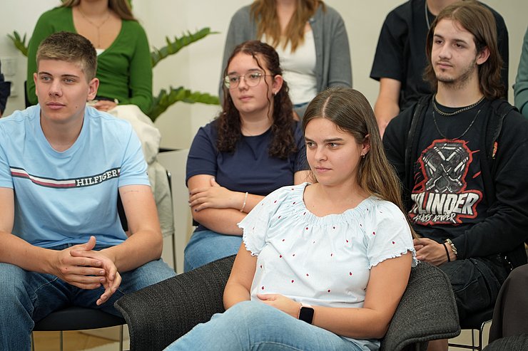 © Land Tirol/Saxl Schülerinnen und Schüler sitzen auf Stühlen hintereinander und hören dem Landeshauptmann zu.
