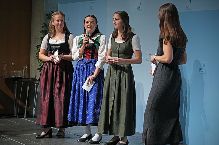 © Land Tirol/Trenker Schülerinnen stehen mit Mikrofon auf Bühne