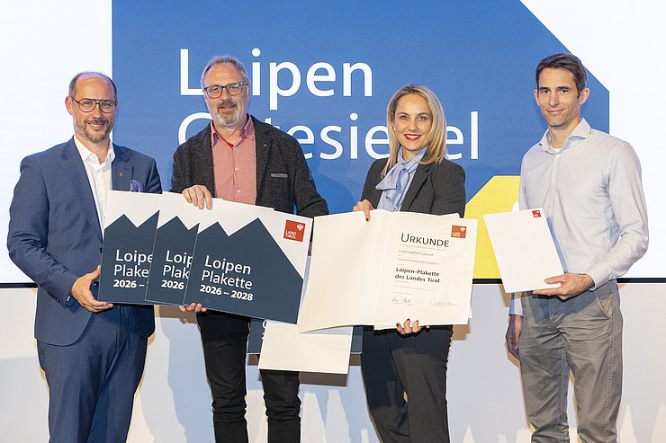 Vier Menschen sind bei einem Gruppenbild zu sehen.