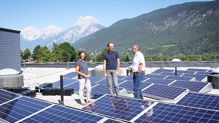 Drei Personen auf einem Dach mit PV-Anlagen