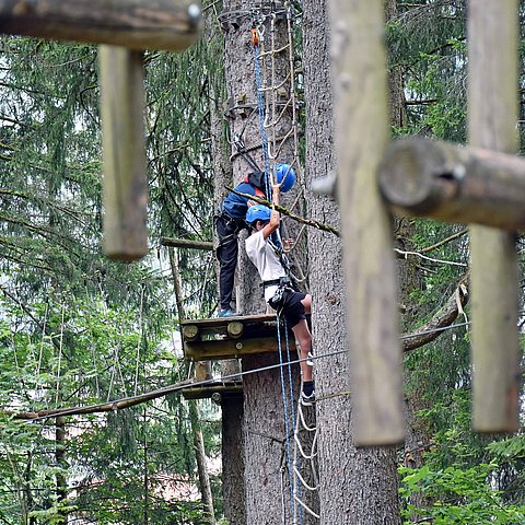 Kindern, die in einem Hochseilgarten klettern.