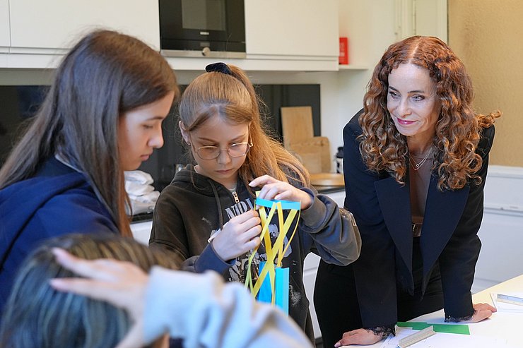 LRin Pawlata schaut zu, wie Mädchen Turm aus Papier bauen