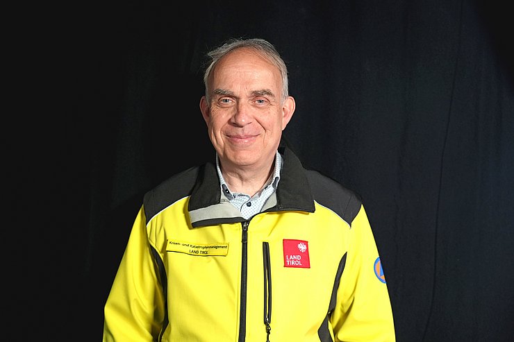 Herr in gelber Jacke vor schwarzem Hintergrund