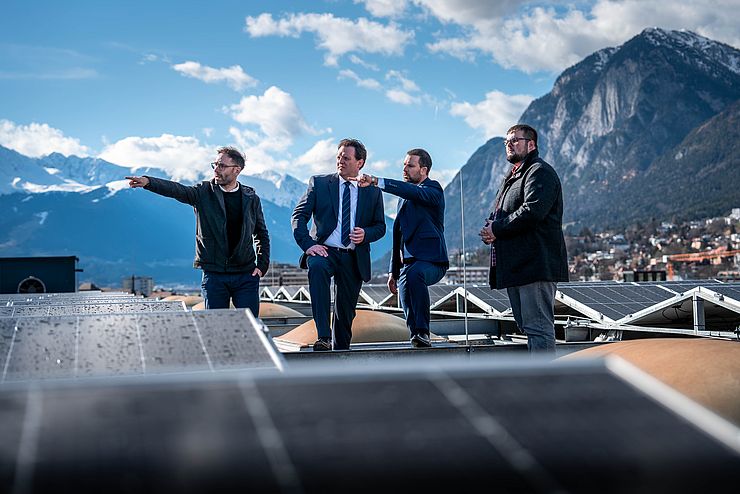 Vier Männer auf Dach des Landhaus; im Hintergrund Stadt Innsbruck; zwei Männer zeigen nach rechts; alle sehen dort hin