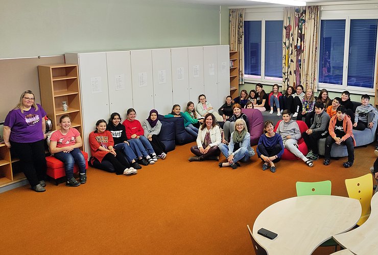 LRin Beate Palfrader (Mitte) las in der Mittelschule Königsweg in Reutte vor. Im Bild mit (li.) Direktorin Myriam Koch und (re.) Edith Müller, Schulqualitätsmanagerin der Bildungsregion Tirol West sowie SchülerInnen der ersten Klassen