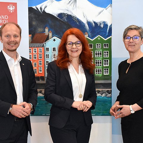 Gruppenfoto der Besprechung im Stadtsenat. Vizebürgermeister Johannes Anzengruber, Landesrätin Cornelia Hagele und Kathrin Eberle - die Vorständin der Abteilung Pflege des Landes - stehen im Sitzungssaal vor einem Gemälde der Stadt Innsbruck. 