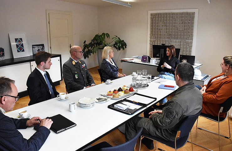Mehrere Personen sitzen am Tisch und unterhalten sich.