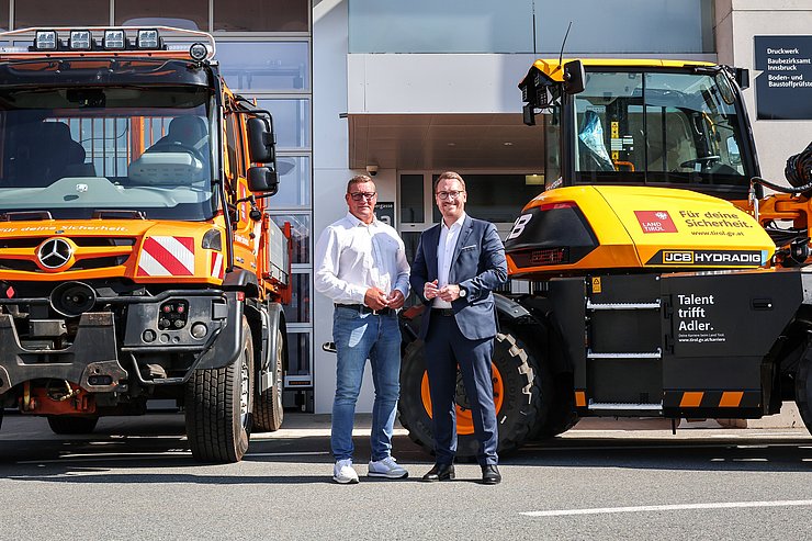 © Land Tirol/Wurnig Zwei Herren stehen vor zwei großen Fahrzeugen für die Straßenerhaltung