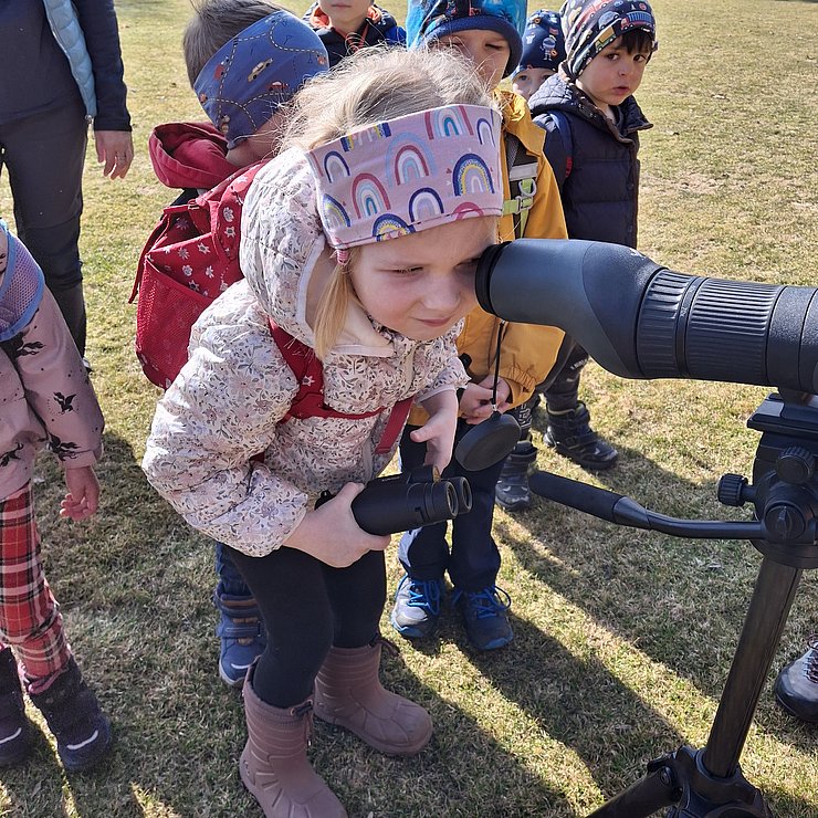 Kind sieht durch Fernglas