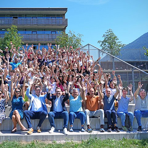Gruppenfoto - Personen sitzen auf Treppe, recken Hände in die Höhe
