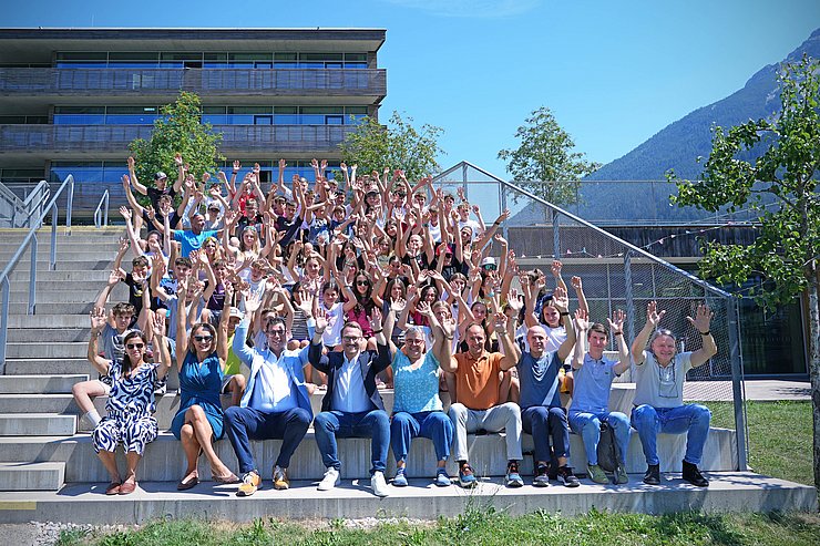 © Land Tirol/Schallhart Gruppenfoto - Personen sitzen auf Treppe, recken Hände in die Höhe