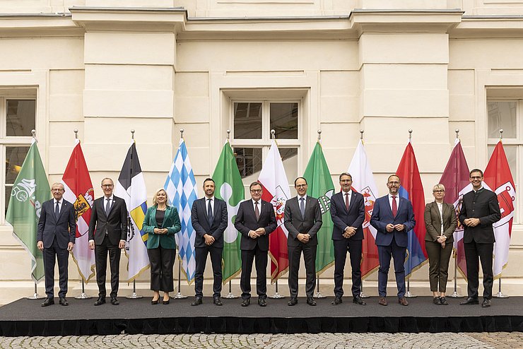 Gruppenfoto vor Fahnen im Freien