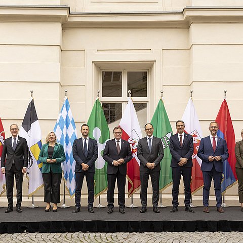 Gruppenfoto vor Fahnen im Freien