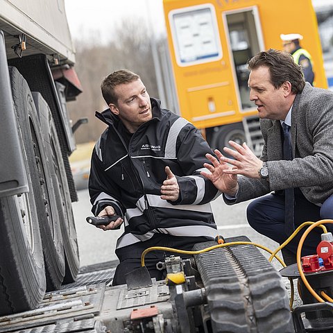 zwei Personen im Gespräch, während Lkw geprüft wird