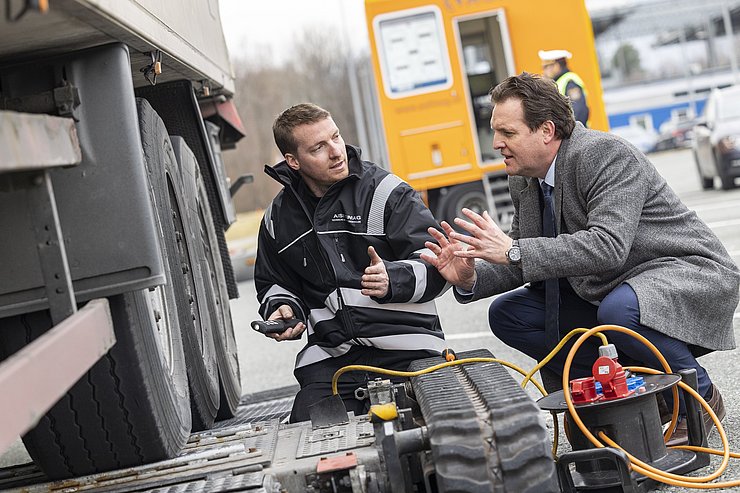 zwei Personen im Gespräch, während Lkw geprüft wird