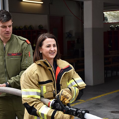 Mair mit Feuerwehrjacke hat Schlauch in der Hand aus dem Wasser kommt