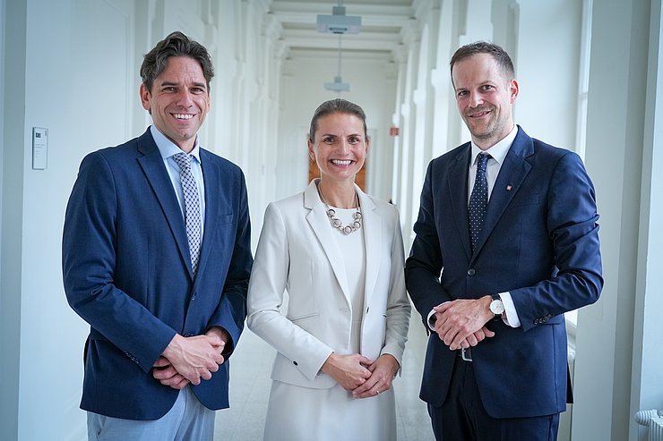 © Land Tirol/Neuner Zwei Herren und eine Dame stehen in einem weißen Gang und lachen in die Kamera.