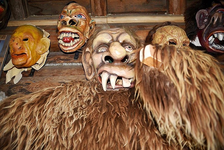 Bretterwand mit aufgehängten Larven im "Klaubaufmuseum im Bäckenstadl" in Lienz, Osttirol.