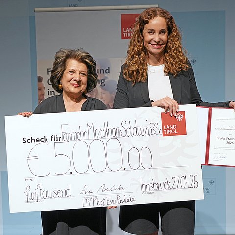 Personen stehen nebeneinander mit Scheck und Urkunde