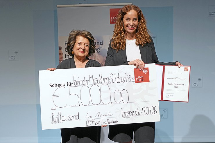 Personen stehen nebeneinander mit Scheck und Urkunde