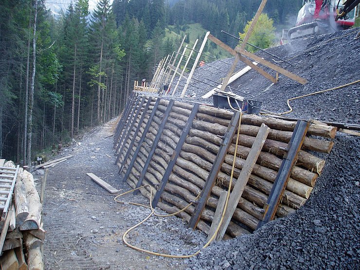 talseitig verankerte Holzstützwand mit begehbarer Berme