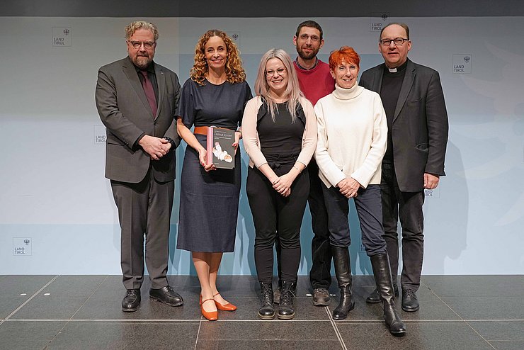 Personen stehen nebeneinander, LRin hält Buch in Händen