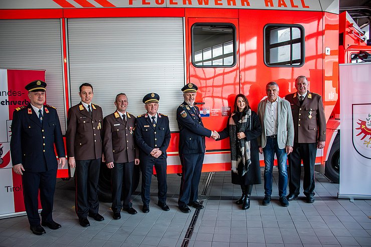 Gruppenfoto vor Feuerwehrauto; meisten personen haben Uniform an; in der Mitte Mair und Sanader, die sich die Hand geben