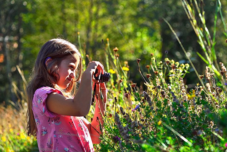 Kleines Mädchen fotografiert eine Blume 