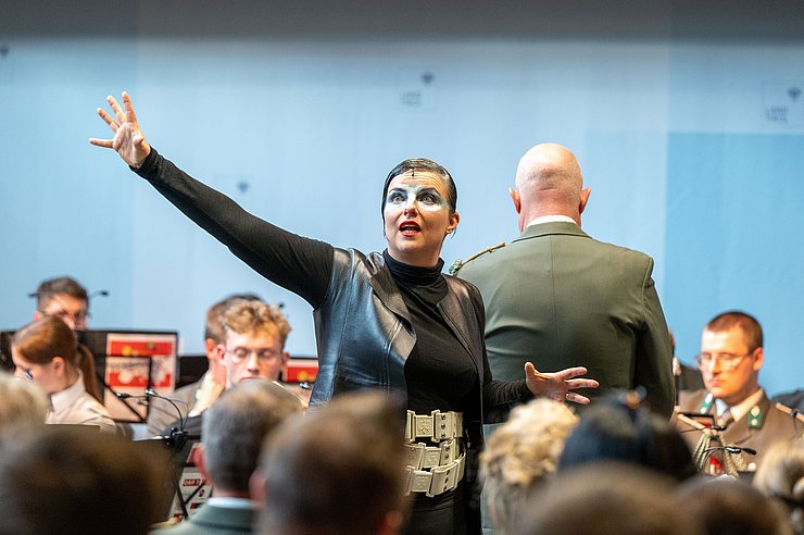 Elisabeth de Roo singt, hinter ihr ist der Militärkapellmeister.
