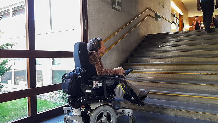 Eine Frau im Rollstuhl vor einer Treppe