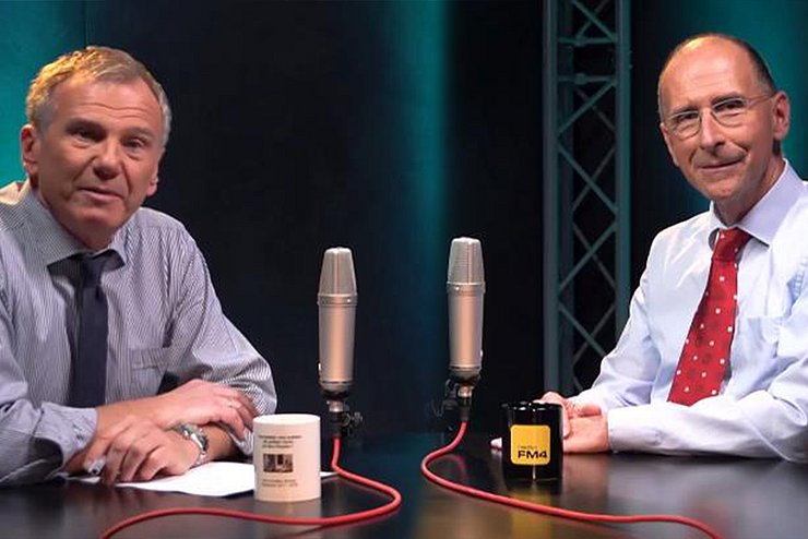 Zwei Moderatoren sitzen sich beim Podcast gegenüber.