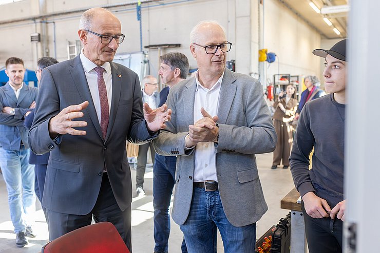 Mattle mit Menschen in Betriebshalle redend