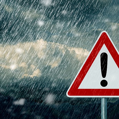 Warnschild (Dreieck mit Rufezeichen); im Hintergrund starker Regen
