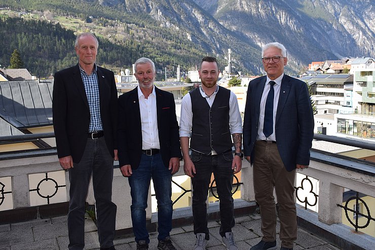 vier Männer nebeneinander auf einem Balkon