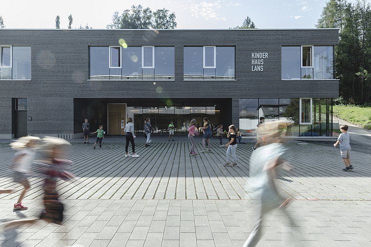 © Mario Webhofer Gehende Menschen vor einem Kinderhaus