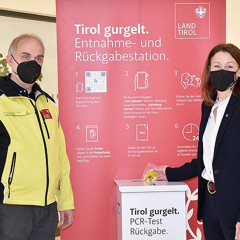 LRin Annette Leja und Elmar Rizzoli vor Rollup "Tirol gurgelt." und Box für Gurgeltests