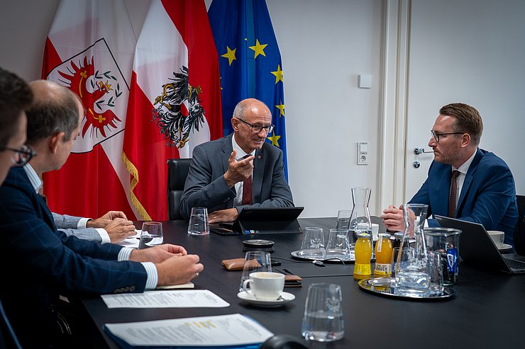 Mehrere Männer sitzen an einem Tisch und unterhalten sich.
