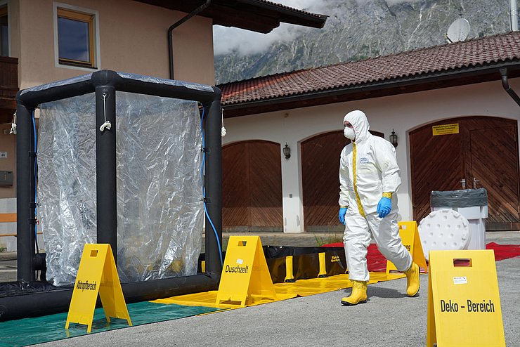 Person in weißem Schutzanzug geht an Schleuse vorbei