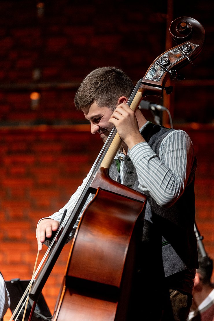 Ein junger Mann in Tracht spielt Kontrabass.