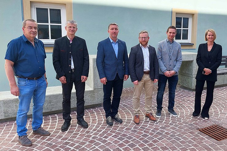 Gruppenfoto der 6 Personen stehend vor hellblauer Hauswand