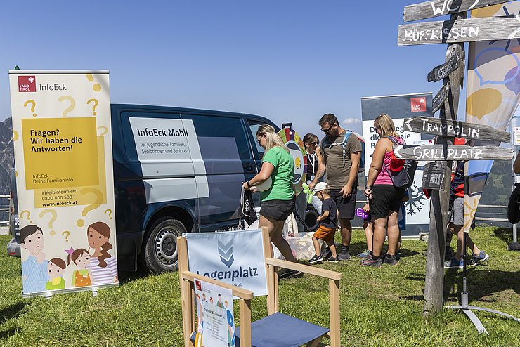 eine Gruppe von Personen vor dem blauen Bus des InfoEck Mobil