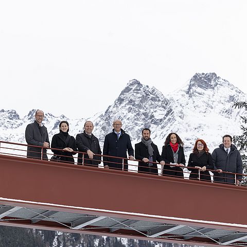 Gruppenfoto der TeilnehmerInnen auf einer Brücke mit Bergen im Hintergrund